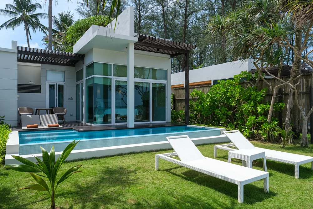 Bahçesinde yüzme havuzu ve şezlonglar bulunan modern, tropik bir villa