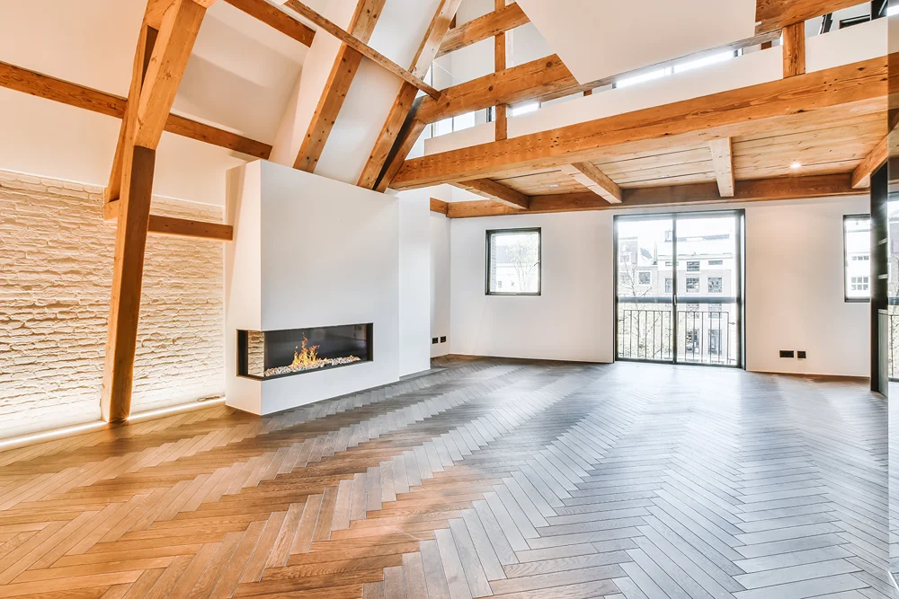Ahşap kirişli, şömineli ve balkon kapılı geniş, aydınlık bir salon